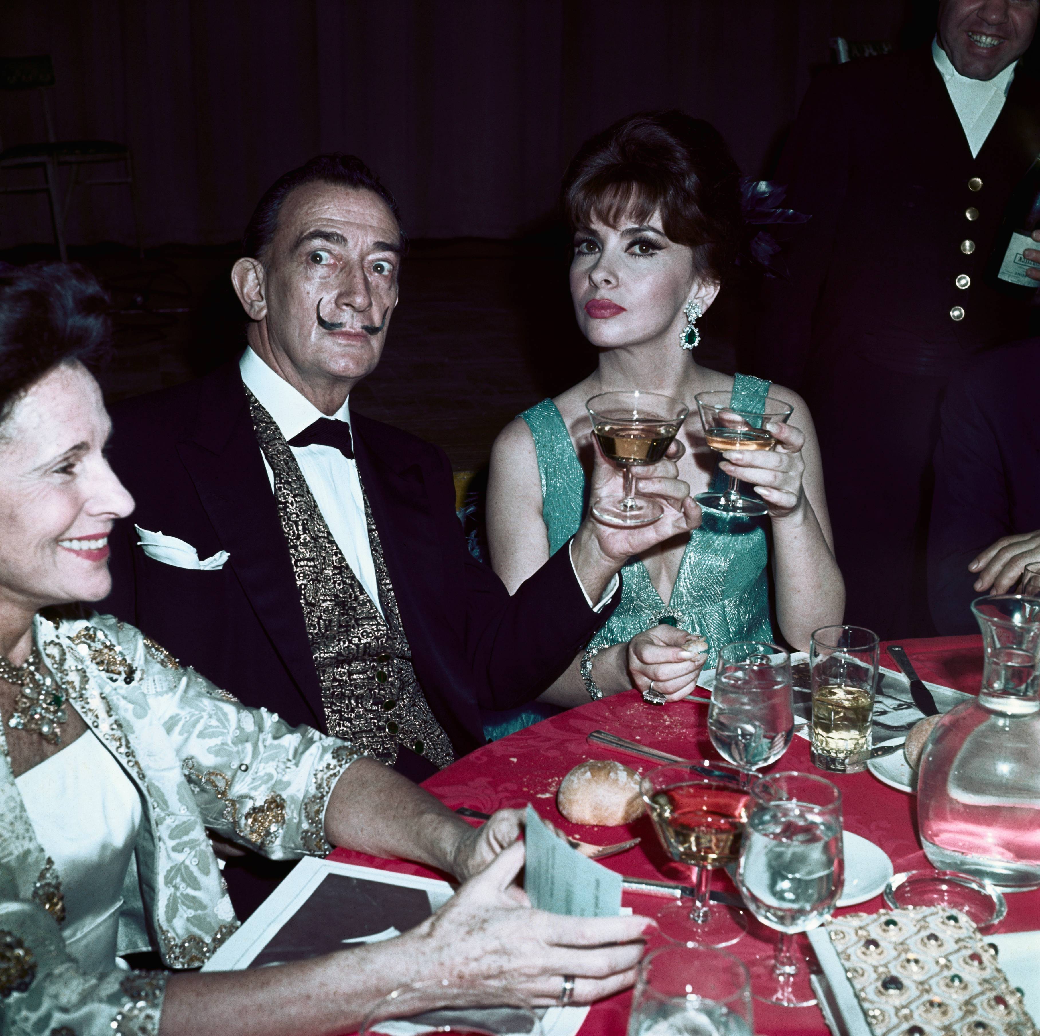 Gala, Salvador Dalí e Gina Lollobrigida brindam à mesa, em 1965