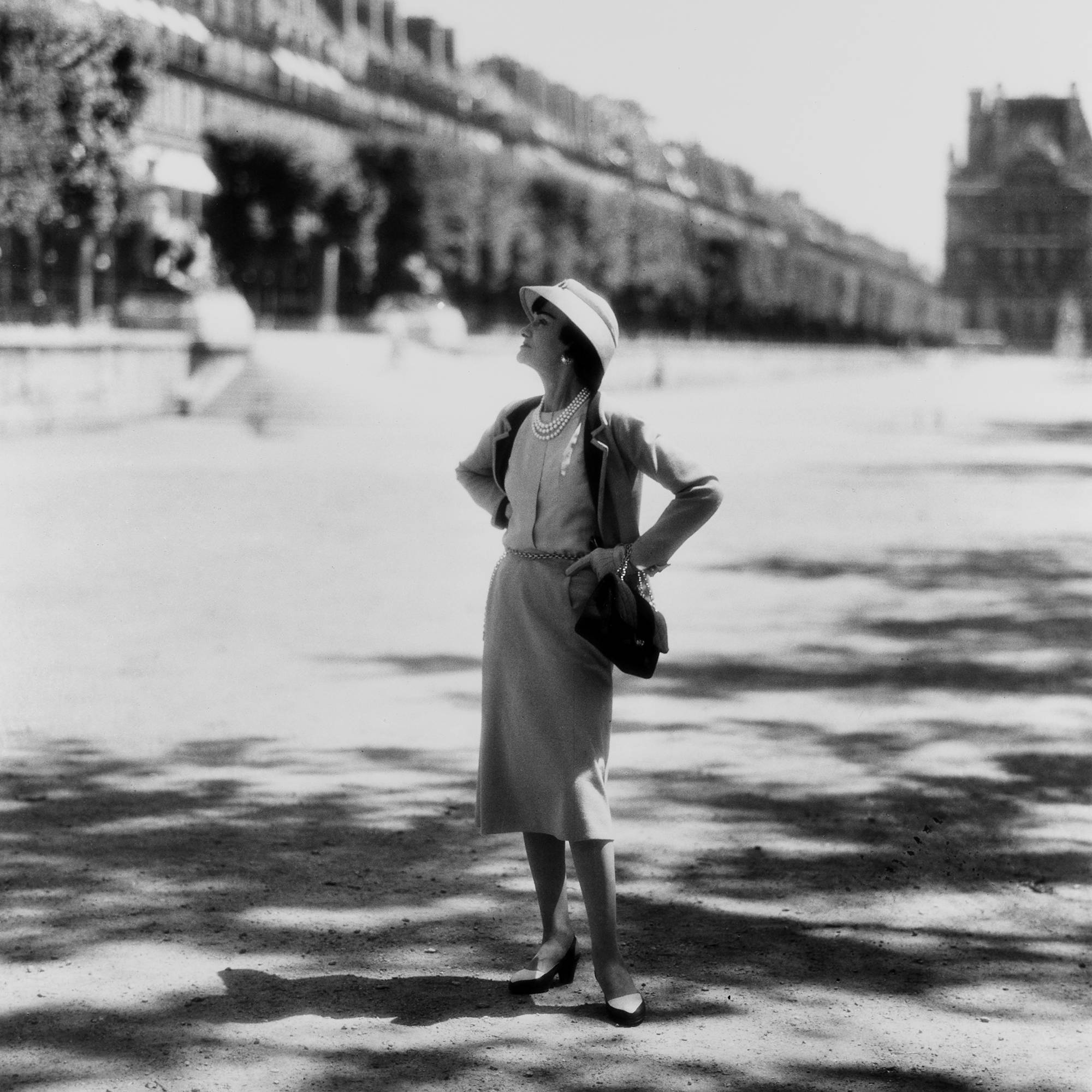 O ano é 1960. Mademoiselle Chanel posa no Jardin des Tuileries, em Paris, com o acessório que ela mesma criou (e que entraria para a história): a bolsa 2.55